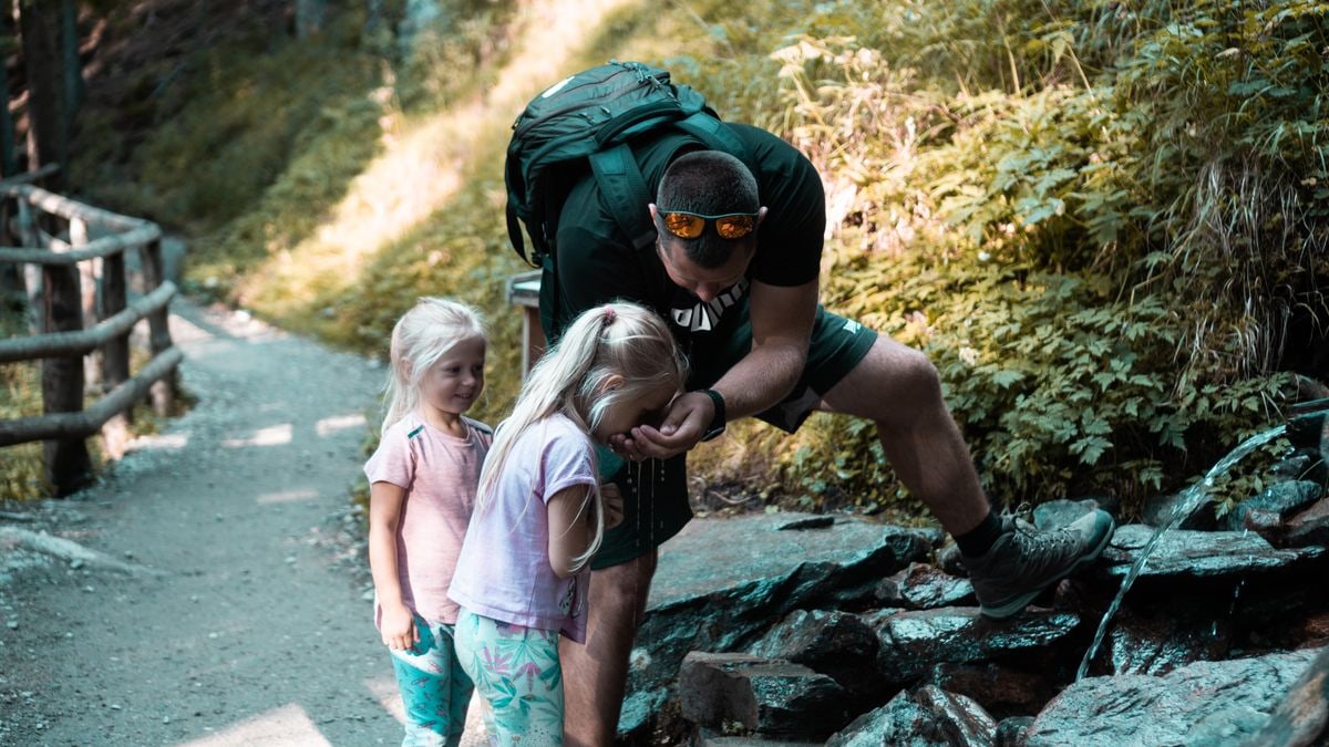 Father with daughters exploring nature on a forest path during a hike.