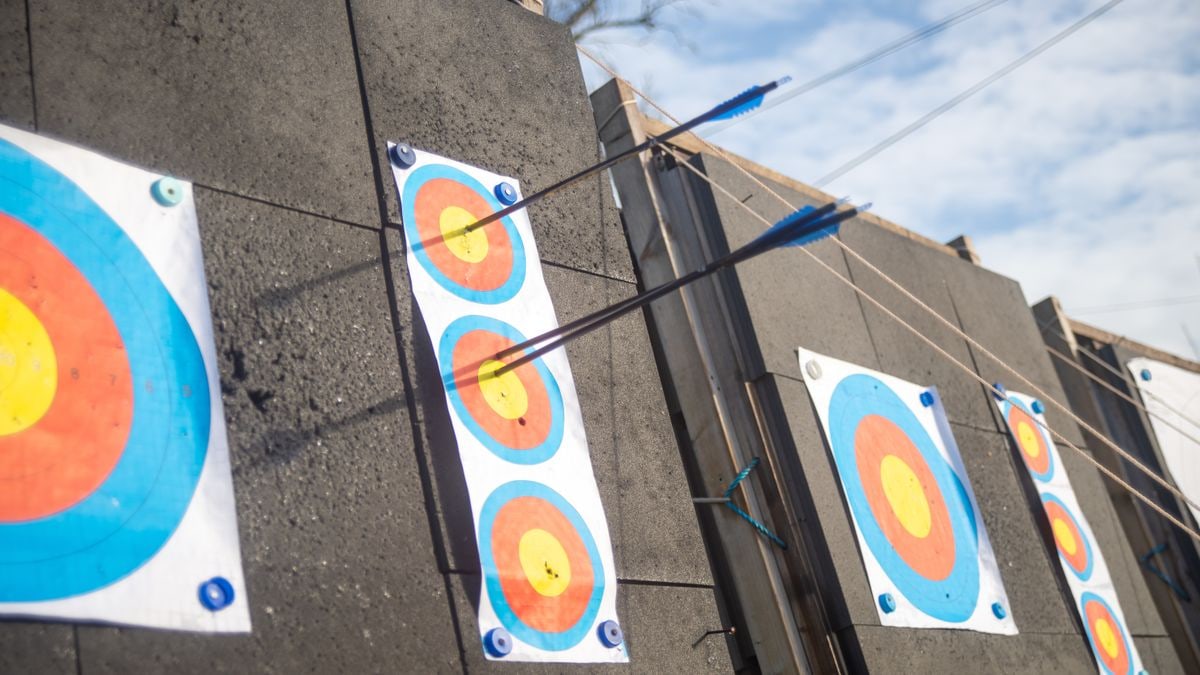 A detailed shot of arrows piercing through colorful archery targets on an outdoor range.